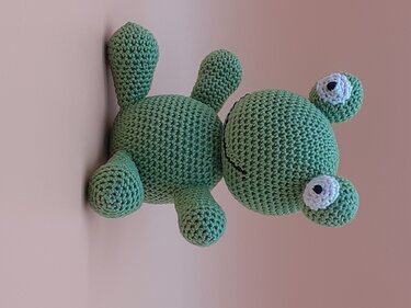 Grüner gehäkelter Amigurumi-Frosch mit aufgesetzten Augen