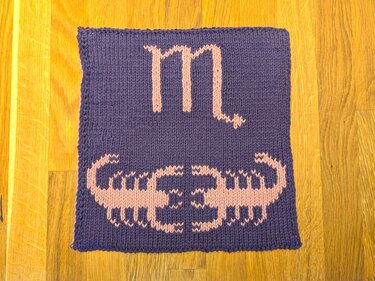 Handgestrickter Topflappen in Violett mit rosa Skorpionmotiv und Sternzeichen-Glyphe
