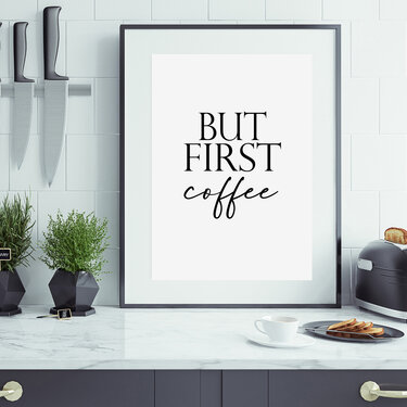 Gerahmtes schwarz-weißes Typografieposter mit dem Text ‚But First Coffee‘ auf einer Küchenarbeitsplatte neben Tasse, Toaster und Kräutern