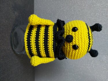 Gehäkelte Amigurumi-Biene mit gelb-schwarzen Streifen auf einem Glasgefäß