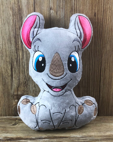Grau gesticktes Nashorn-Kuscheltier mit großen blauen Augen vor Holzuntergrund