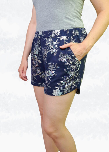 Seitliche Ansicht einer Person in dunkelblauen Shorts mit floralem Muster, seitlichen Eingrifftaschen und elastischem Bund
