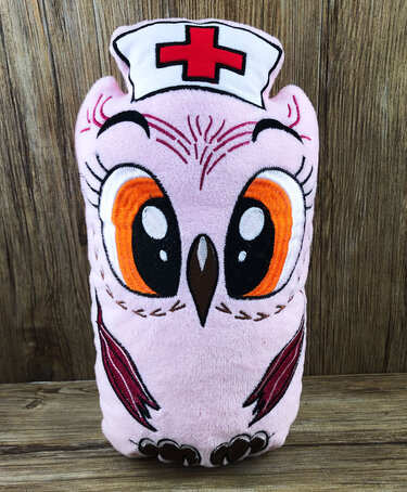 Rosa bestickte Plüscheule mit Krankenschwesterhaube und rotem Kreuz vor Holzhintergrund
