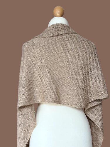 Rückansicht eines beigefarbenen gestrickten Dreieckstuchs mit Rippen- und Lochmuster auf Schneiderpuppe