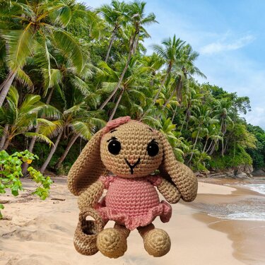 Gehäkelter Amigurumi-Hase im rosa Kleid mit kleiner Tasche.