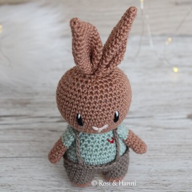 Brauner gehäkelter Amigurumi-Hase mit langen Ohren, mintgrünem Shirt und brauner Latzhose