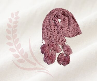 Gehäkelter mauvefarbener Schal mit Bommeln auf hellem Hintergrund