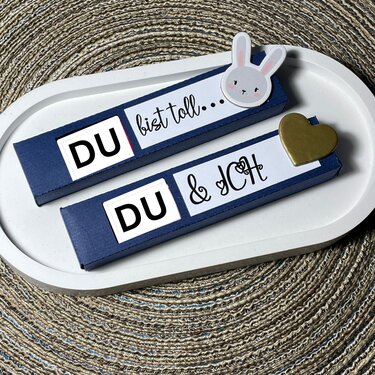 Dunkelblaue Geschenkboxen mit weißen Plott-Etiketten 'DU bist toll' und 'DU & ICH' auf ovalem Tablett