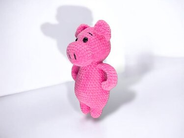 Rosa gehäkeltes Amigurumi‑Schwein aus kuscheligem Garn, stehend mit Armen an der Seite