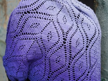 Nahaufnahme eines lila gehäkelten Tuchs mit Farbverlauf und durchbrochenem Rautenmuster