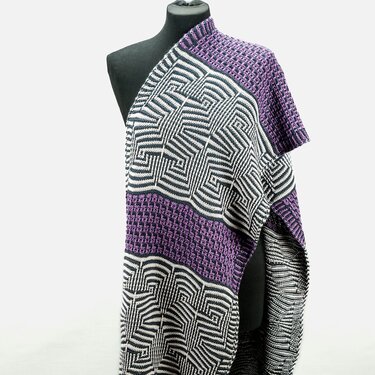 Knitted shawl on a mannequin with black-and-white geometric patterns and purple textured bands.