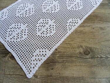 Weißer gehäkelter Filet-Tischläufer auf Holzoberfläche