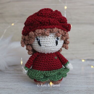 Gehäkelte Amigurumi-Puppe mit roter Mütze, rotem Oberteil und grünem Rüschenrock