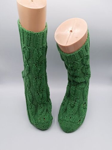 Paar grüne gestrickte Socken mit Zopfmuster auf Schaufenster-Beinformen
