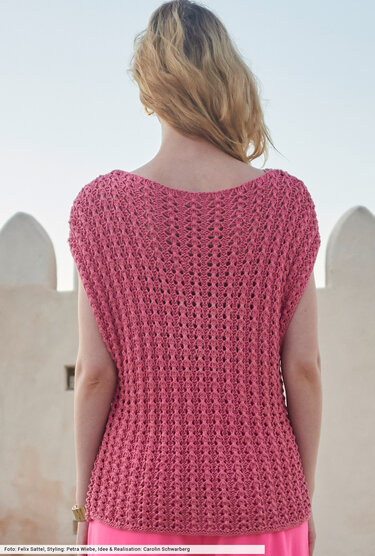 Rückansicht einer Frau in einem rosafarbenen, gestrickten Top mit Lochmuster.