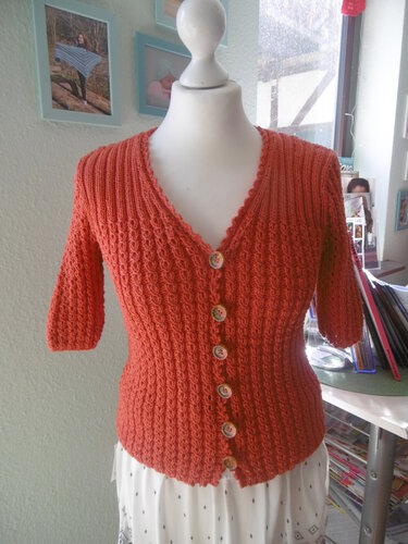 Korallefarbene kurzgeschnittene Strickjacke mit V-Ausschnitt und sieben Knöpfen auf Schaufensterpuppe