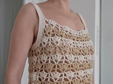 Nahaufnahme eines gehäkelten Damen-Tops mit Muschelmuster in Beige und Creme.
