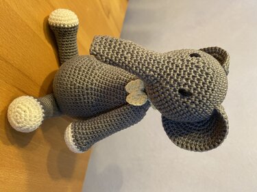 Gehäkelter grauer Amigurumi-Elefant mit hellen Pfotenabschlüssen