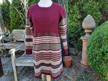 Langärmeliges Strickkleid in Bordeaux und mehrfarbigen Streifen auf einer Schaufensterpuppe