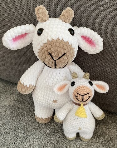 Großes und kleines weiß‑braunes Amigurumi‑Schaf nebeneinander, kleines Schaf mit gelbem Glöckchen