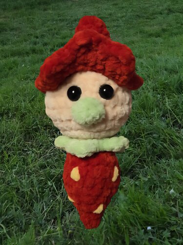 Gehäkeltes Amigurumi Pilz-Wichtel mit roter Mütze auf Gras