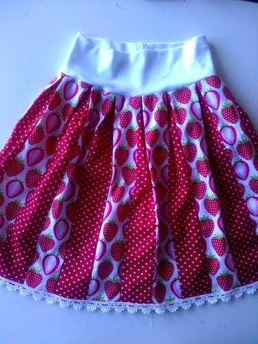 Plissierter Kinderrock mit abwechselnden Erdbeer- und Punktemotiven, weißem Bund und Spitzenborte.