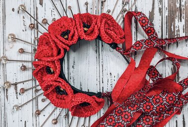 Headband with red crocheted flowers, metal rods with faceted beads, and red patterned ribbon ties on white distressed wood