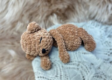 Nahaufnahme eines gehäkelten beigen Teddys mit gestickten Augen