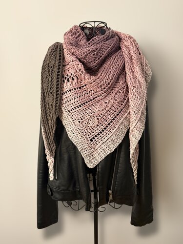 Crocheted triangle shawl with gradient colors from dark taupe to pale pink, draped on a mannequin over a black jacket.