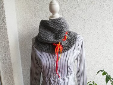 Detailaufnahme eines grauen Loops mit Rippenbund und orange-gelber Schnürung