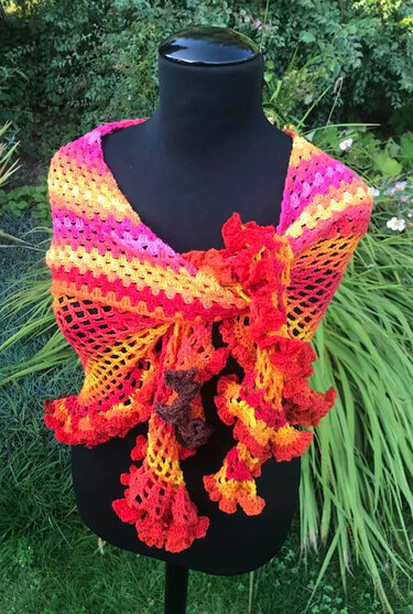 Gehäkeltes Dreieckstuch in Gelb-Orange-Pink mit Rüschen auf schwarzer Schaufensterpuppe