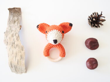 Gehäkelte Fuchsrassel mit Holzring neben Naturdekoration