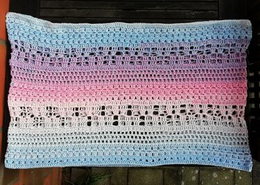 Gehäkelter Schal in Pastellfarben mit Blau-, Lila-, Rosa- und Weißverlauf und Lochmuster.