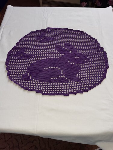 Rundes violettes Filethäkel-Deckchen mit Hasenmotiv auf hellem Tuch.