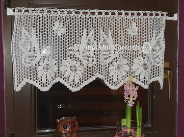 Weiße gehäkelte Scheibengardine mit Filet-Häkelmuster und Zackenabschluss am Fenster