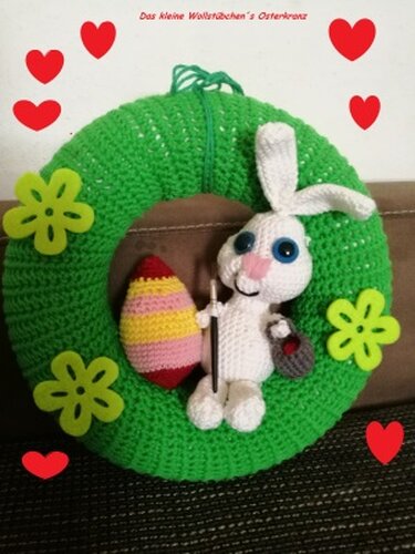 Grüner gehäkelter Osterkranz mit weißem Häschen, gestreiftem Osterei und grünen Blumenapplikationen.