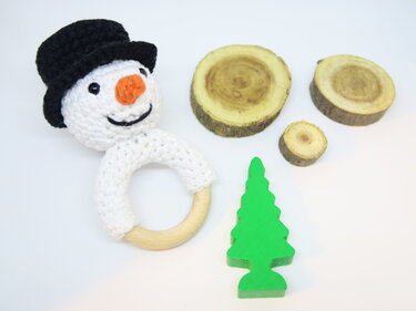 Gehäkelter Schneemann-Greifring mit Holzring, Holzscheiben und grünem Holzbaum