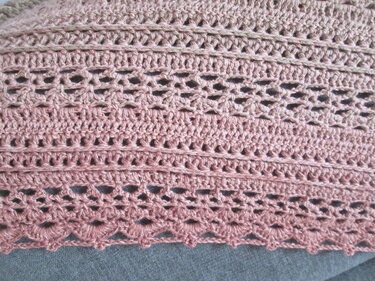 Nahaufnahme eines altrosafarbenen Häkelmusters mit dichten Reihen, Lochmustern und Muschelsaum