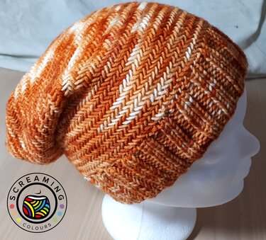 Gestrickte orange Beanie mit Zickzackmuster auf weißem Schaufensterkopf