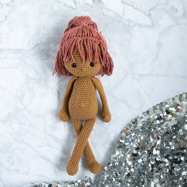 gehäkelte Amigurumi-Puppe mit rosafarbenem Garnhaar, liegend