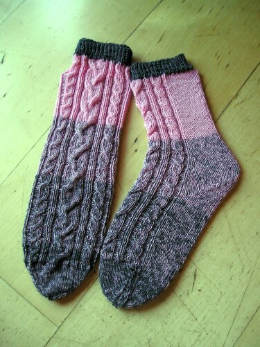 Gestrickte Damensocken rosa-grau mit Zopfmuster auf Holzboden