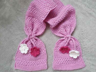 Rosa gestrickter Kinderschal mit zwei Täschchen und weißen sowie dunkelrosa Häkelblüten