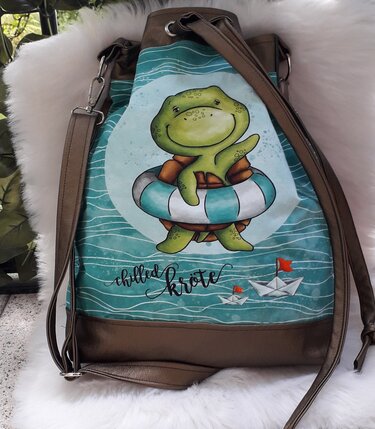 Türkis-braune Beuteltasche mit lächelnder Schildkröte im Rettungsring, Wellenmuster und Papierbooten.