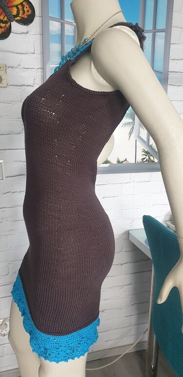 Seitenansicht eines taillierten, ärmellosen dunkelbraunen Strickkleids mit blauem Häkelrand an einer Schaufensterpuppe