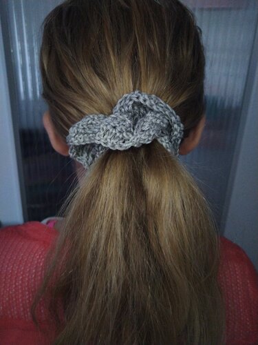 Rückansicht einer Person mit blondem Pferdeschwanz, gehalten von einem grauen gehäkelten Scrunchie.