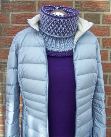 Kragenschal in Lila und Hellblau mit kombiniertem Struktur- und Rippenmuster, über einem lila Oberteil und einer hellblauen Jacke getragen