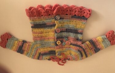Gehäkelte Babyjacke in Pastellstreifen mit Rüschenkragen und Blumenknöpfen