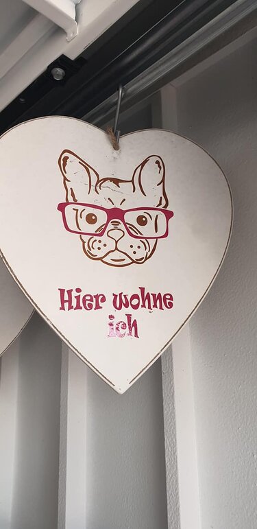 Herzförmiges Schild mit zweifarbiger Bulldoggengrafik (braun/rosa) und Schriftzug 'Hier wohne ich'