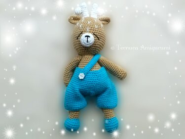 Handmade amigurumi fawn with closed embroidered eyes and white forehead markings wearing a turquoise romper on a soft starry background