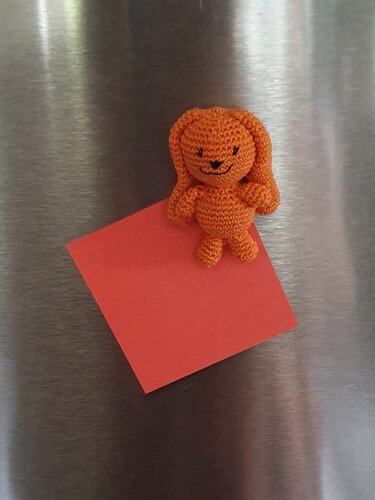 Kompakte orange gehäkelte Figur als Notizhalter auf Metall